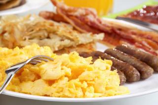 A breakfast plate of sausage, eggs, bacon, and potatoes