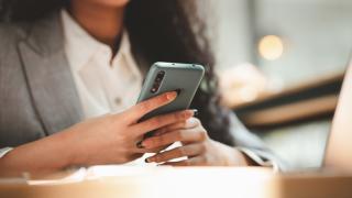 Close up of a woman in a suit holding a smartphone